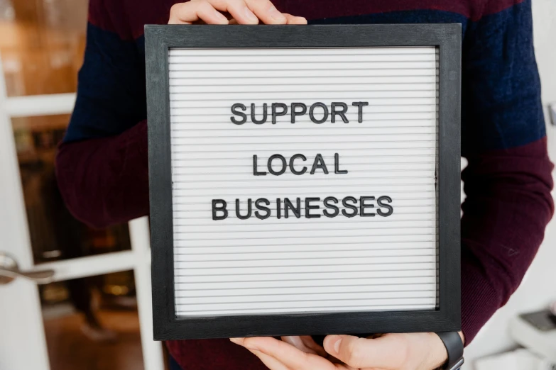 a man holding up a sign saying support local businesses