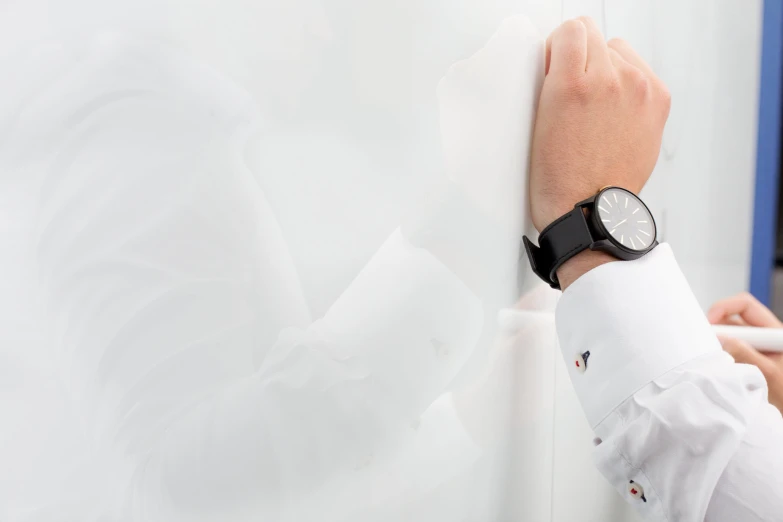 a person wearing a black and white watch and holding his hand near the wall