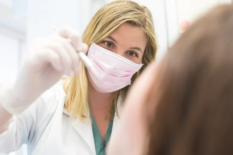 a woman wearing a mask and putting on a surgical mask
