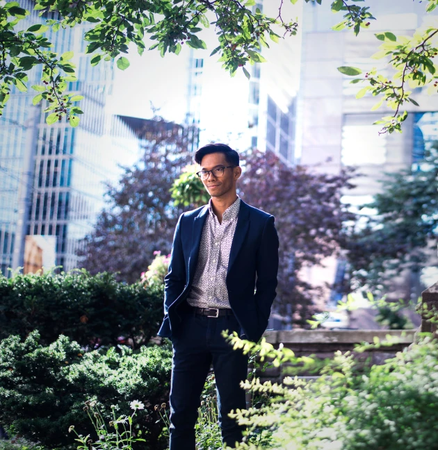 man in suit standing by bushes looking at camera