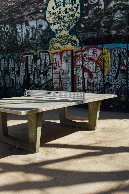 a ping pong table set up in front of a grafitti wall