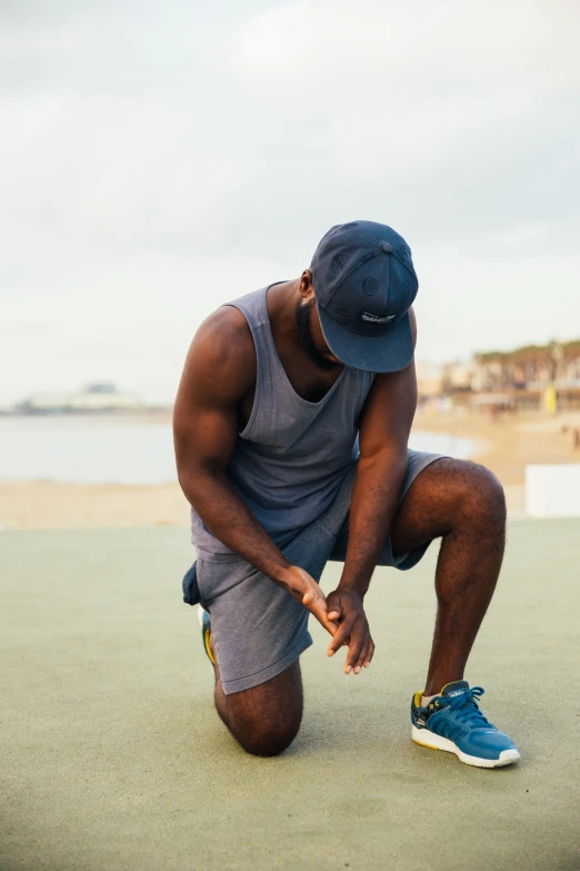 a man with a blue hat on tying his tennis shoes