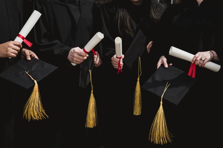 graduates from left to right holding diplomas in hand