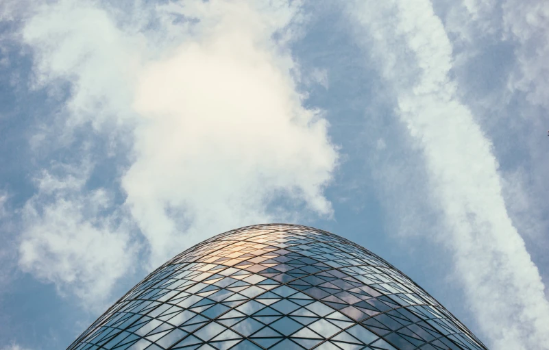 a tall glass building that is under a cloudy sky