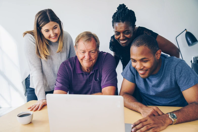 group of adults looking at laptop screen at table