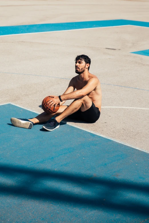 a man sitting on the basketball court with his feet propped up