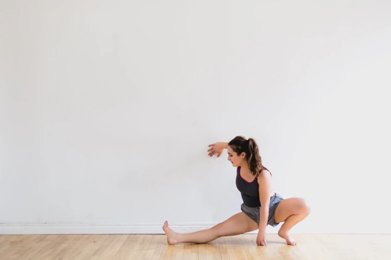 young woman stretching on the floor in front of a white wall
