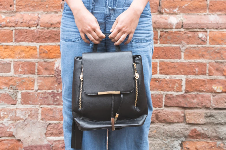 a woman holding a small black backpack and purse