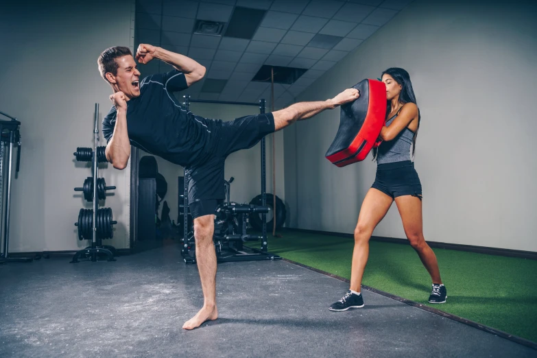 a man kicking a girl on the leg with boxing gloves