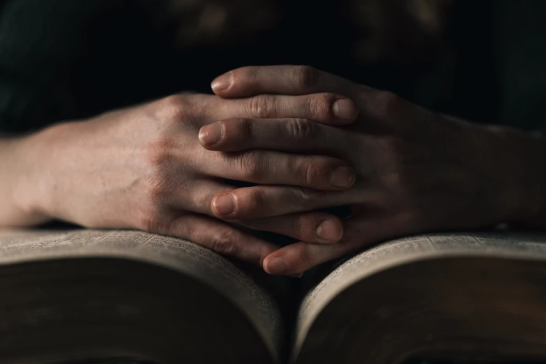 close - up s of praying hands on an open bible