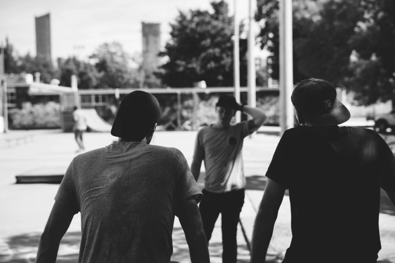 three guys on a skate board park walking toward the camera