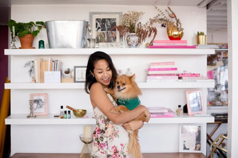 a woman holding a dog with white shelves in the background