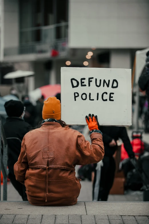 a person holding a sign that says defund police
