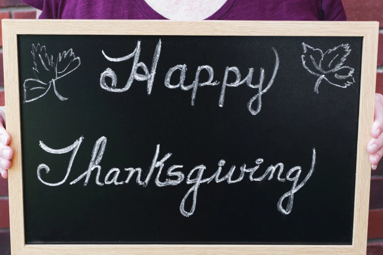 a man holding a chalkboard that says happy thanksgiving