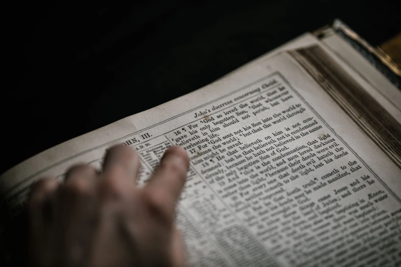 a hand is holding a book open to a page