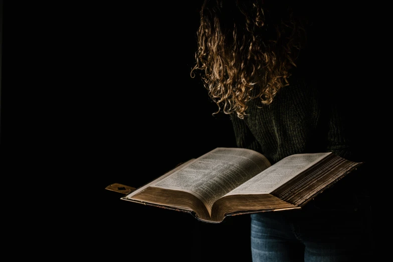 a woman is holding an open book and looking at it