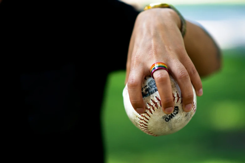 woman hand with painted baseball ball, wearing yellow ring