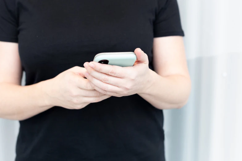 a woman in a black t - shirt is holding a cell phone