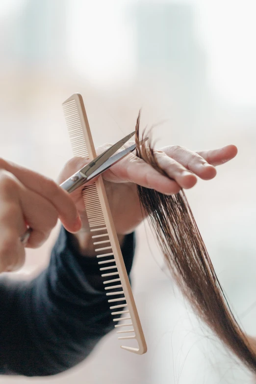 a woman holding a comb and scissors  her hair