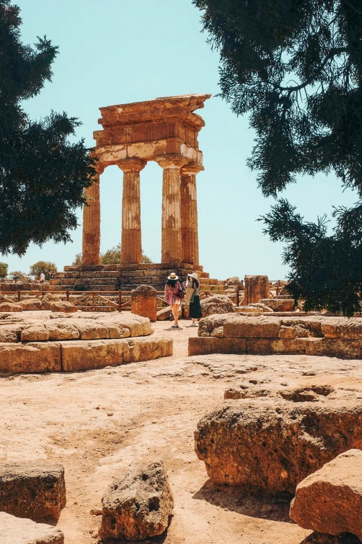 two people in front of a large stone structure