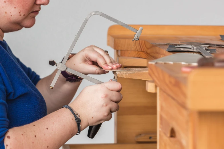 a woman working on a wooden table holding pliers