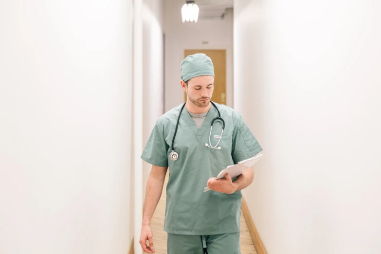 man in scrubs using electronic tablet on hallway