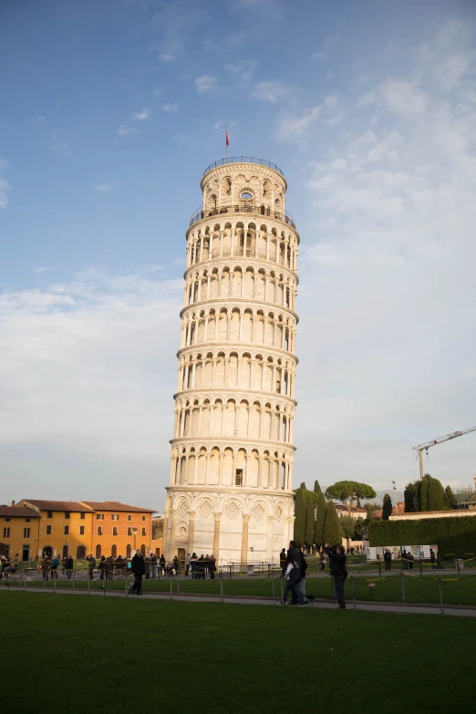 an old leaning tower that has people around it