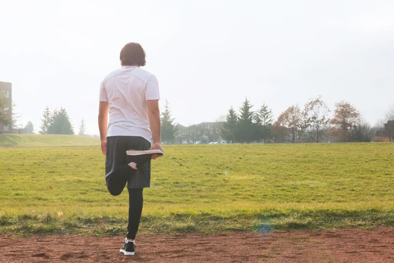 a young man holding a frisbee walking on a field