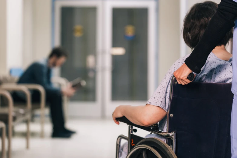 a woman in a wheelchair and a man looking at their phone