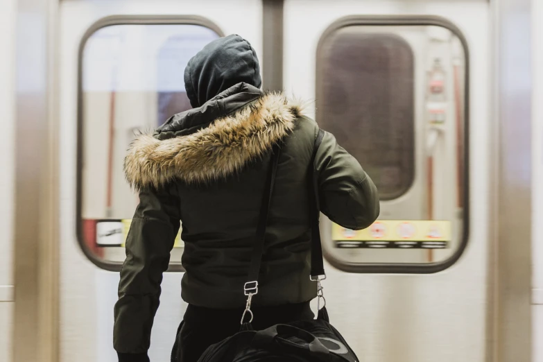 a man with a backpack in his hand walking toward a subway