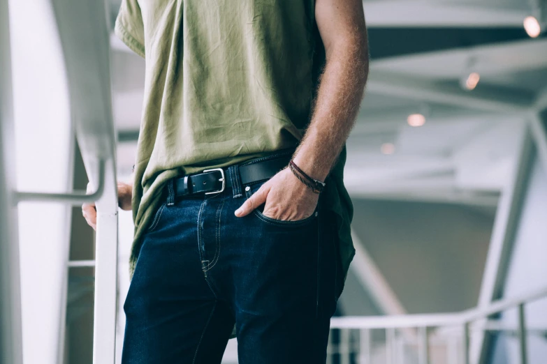 a man standing wearing a belted green t - shirt