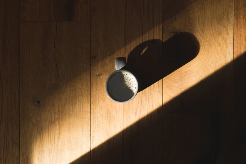 a shadow on a wooden floor casting a sun light onto a vase