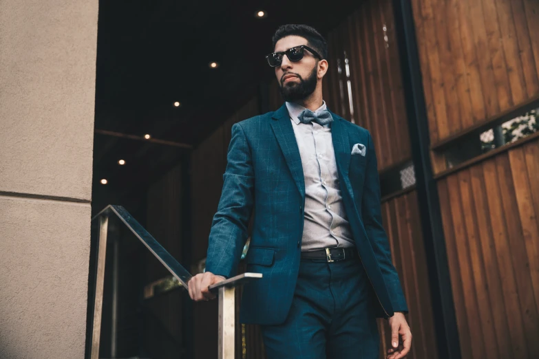 a man in a blue suit standing in front of stairs