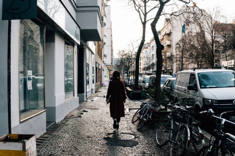 a person walks on the side walk by some parked bikes