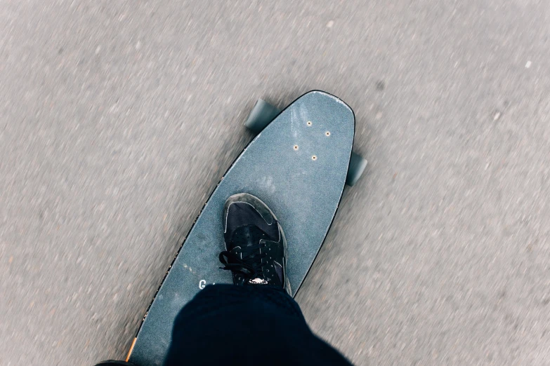 the top view of a man in black shoes riding a skateboard