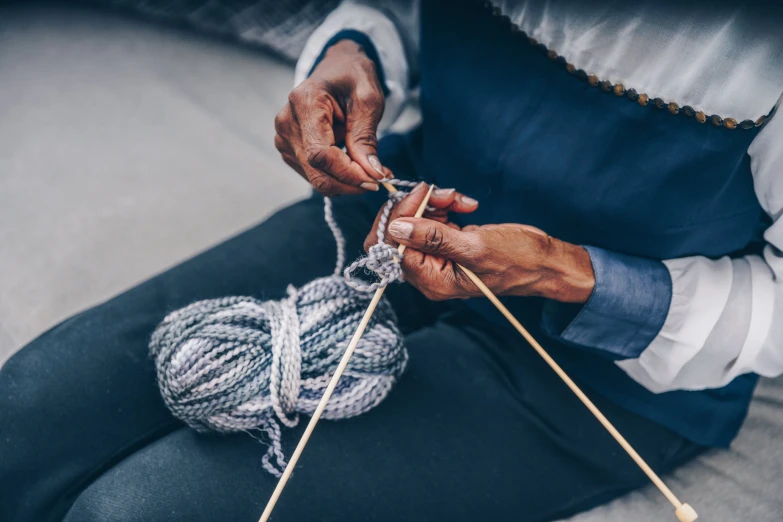 the man is knitting with two skewers