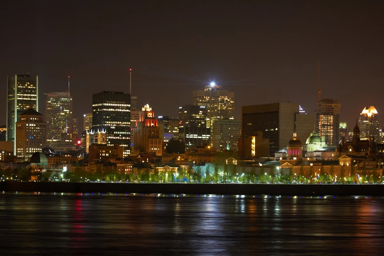 a city skyline at night with lights reflected on the water