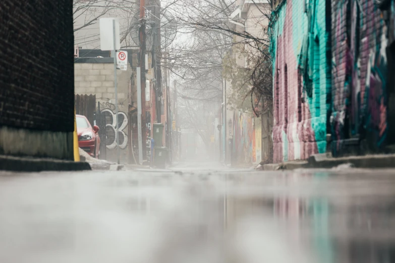 a very quiet and drizzled street next to some very colorful buildings