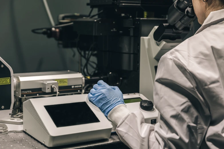 a person wearing white clothes using a machine to check the sample size of soing