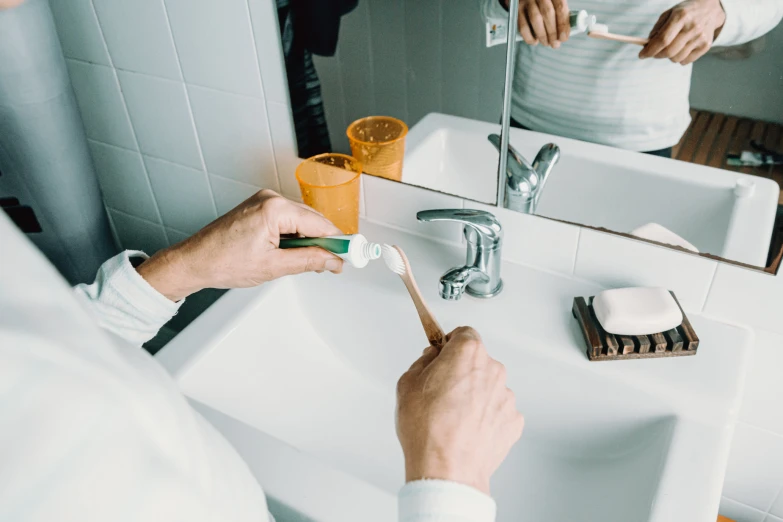 a man is brushing his teeth at the bathroom sink