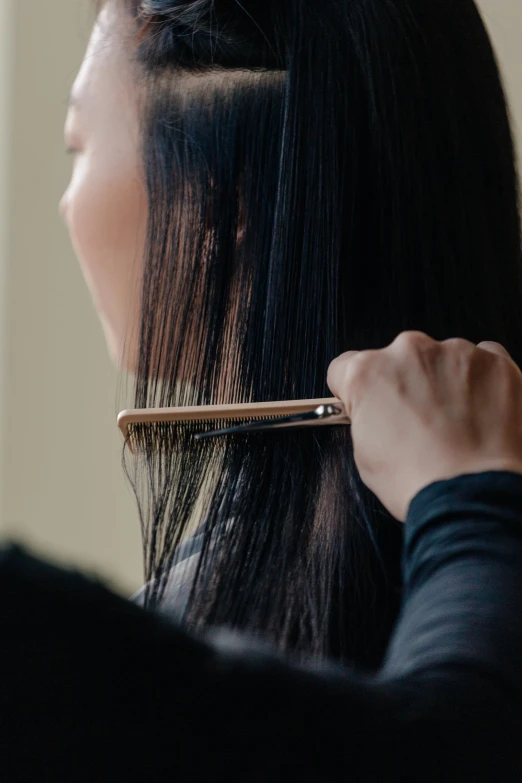 a woman holding a comb up to her hair