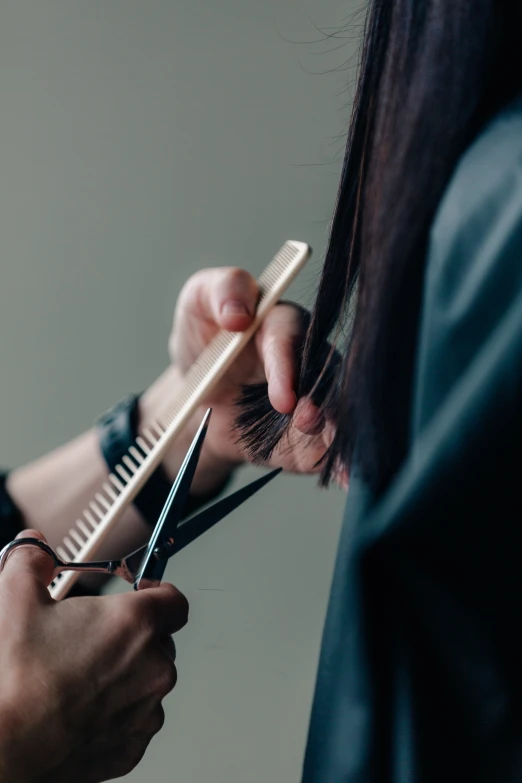 a person  another persons hair using a pair of scissors