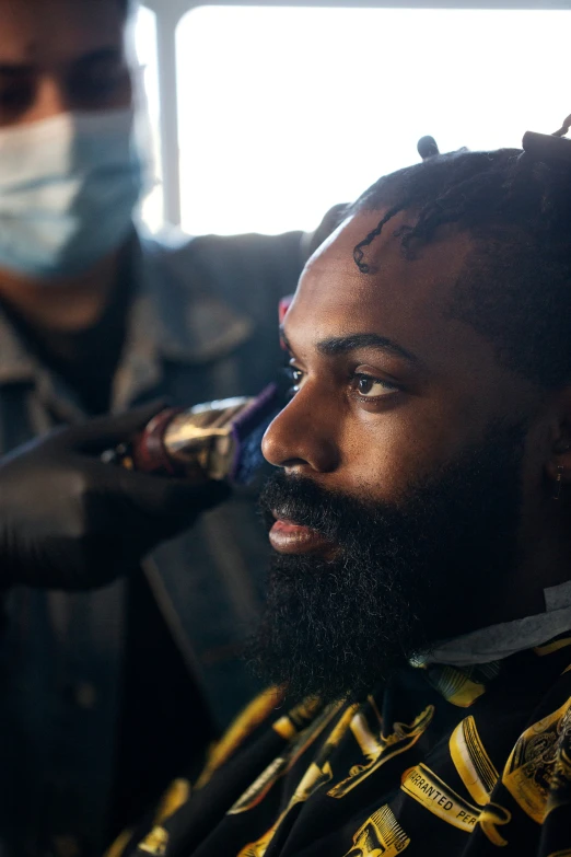 barber doing a man's hair in front of window