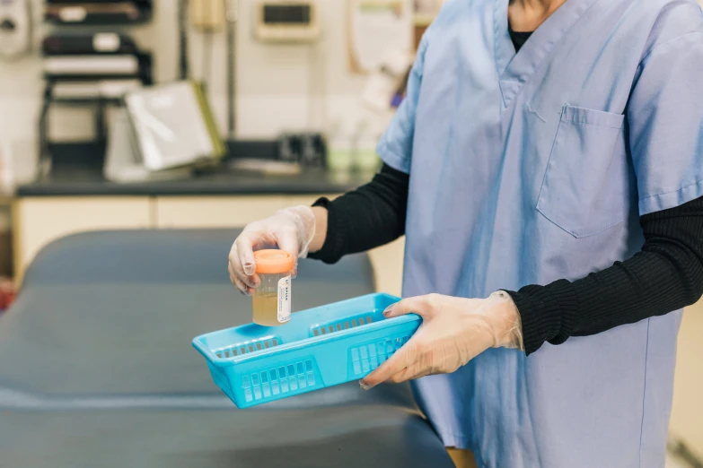 a person in scrubs is handling a container