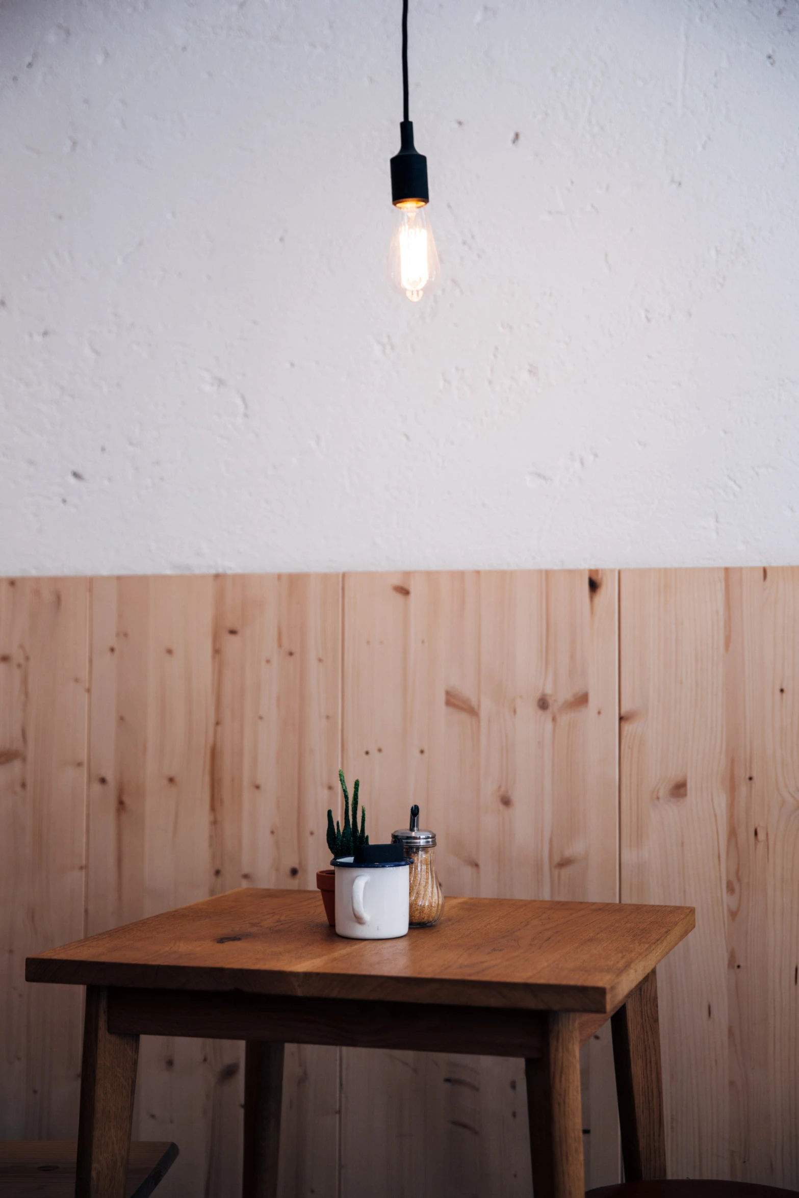 an empty table is lit with light bulb hanging overhead