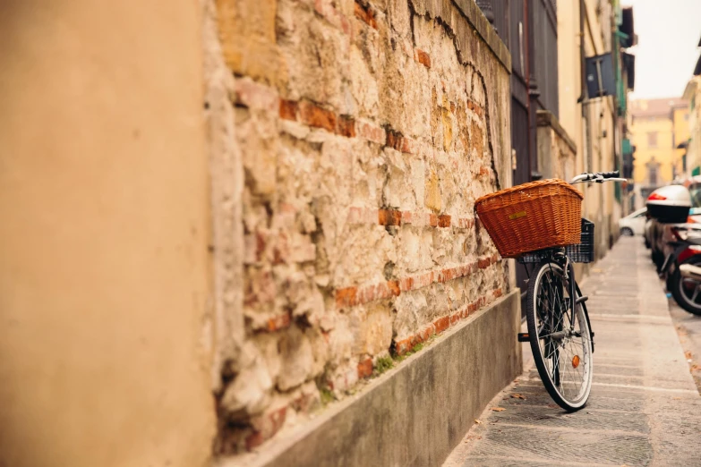 a bicycle sitting against a wall by a sidewalk