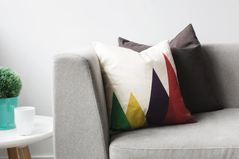 an eclectic rainbow pillow sits on a gray couch