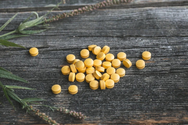 small yellow pills in front of green plant