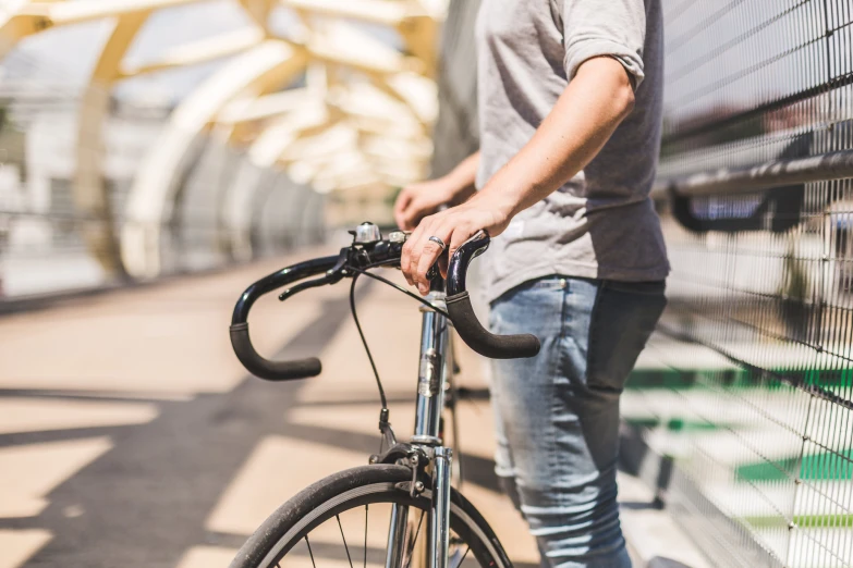 a man holding onto his bike while standing near the wall