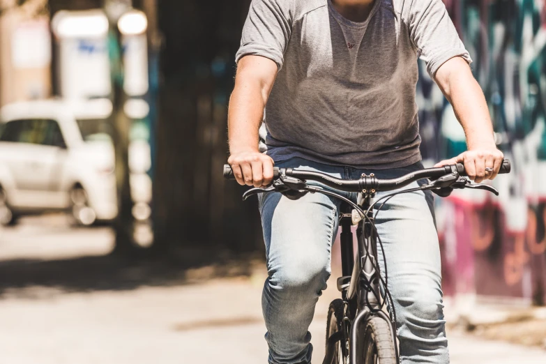 a man in cap and jeans riding a bicycle